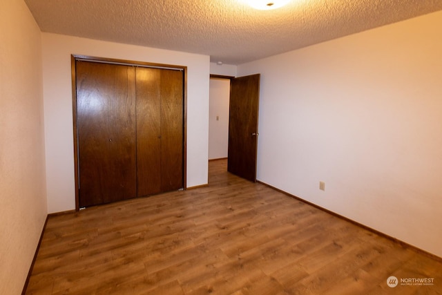 unfurnished bedroom with hardwood / wood-style flooring, a textured ceiling, and a closet