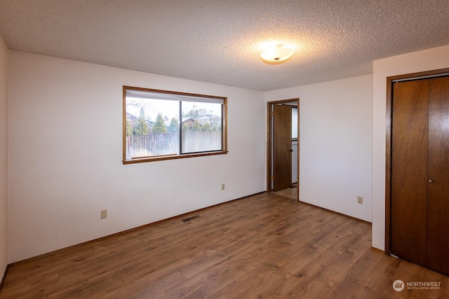 unfurnished bedroom featuring a textured ceiling, hardwood / wood-style flooring, and a closet