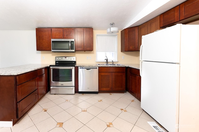 kitchen with light stone countertops, sink, and appliances with stainless steel finishes