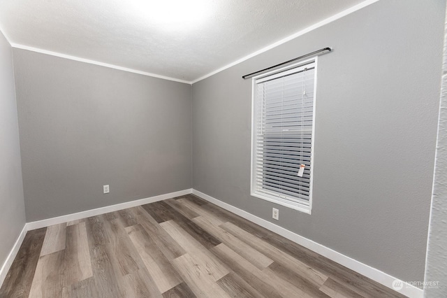 empty room with ornamental molding and hardwood / wood-style flooring