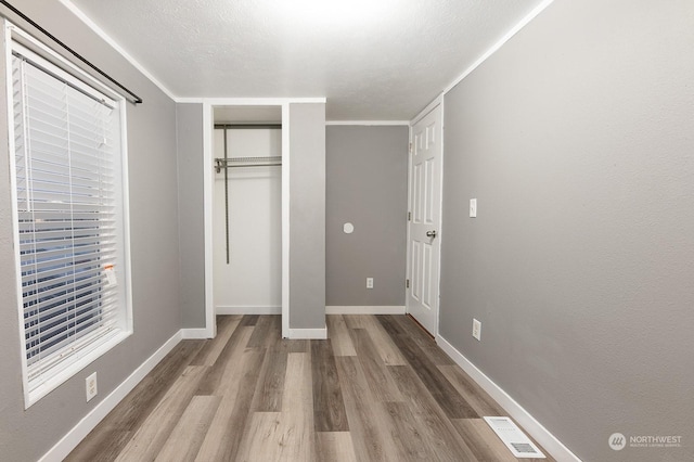 unfurnished bedroom with a textured ceiling, a closet, and hardwood / wood-style flooring