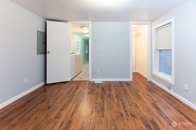 spare room with a textured ceiling, electric panel, hardwood / wood-style floors, and washer and dryer