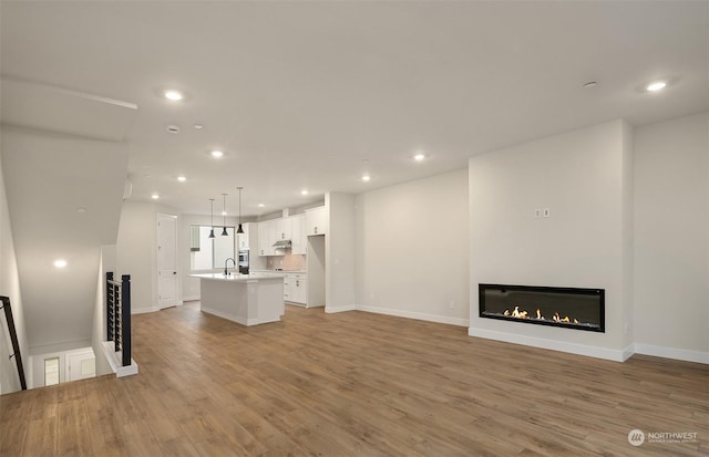 unfurnished living room with sink and light hardwood / wood-style floors