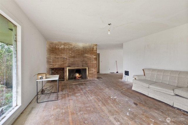 living room featuring heating unit, wood-type flooring, and a brick fireplace