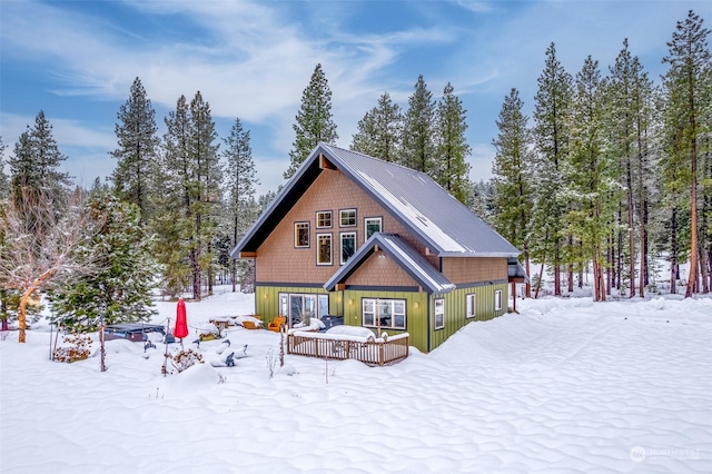 snow covered rear of property featuring a deck