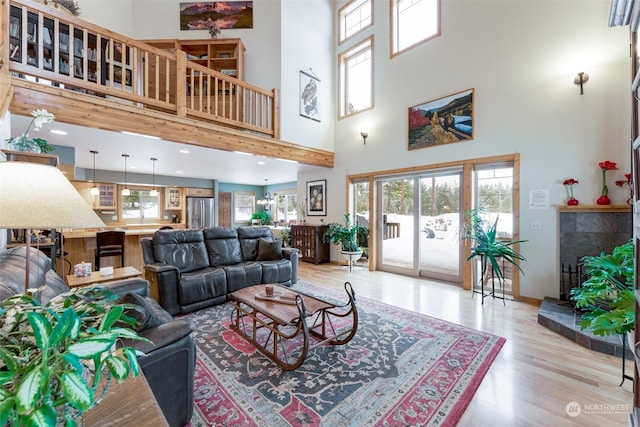 living room with a fireplace, a high ceiling, and light wood-type flooring