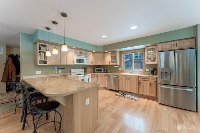 kitchen featuring a breakfast bar, sink, light brown cabinetry, kitchen peninsula, and stainless steel appliances