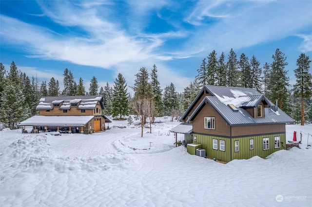 snow covered back of property featuring central air condition unit