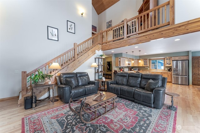 living room with light hardwood / wood-style floors, high vaulted ceiling, and wooden ceiling