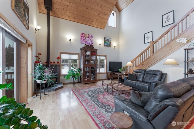 living room featuring a wood stove, light hardwood / wood-style flooring, high vaulted ceiling, and wooden ceiling