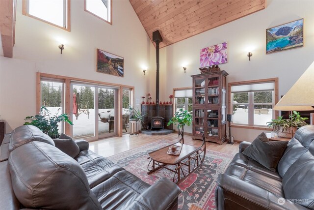 living room with wood ceiling, a healthy amount of sunlight, a wood stove, and a towering ceiling