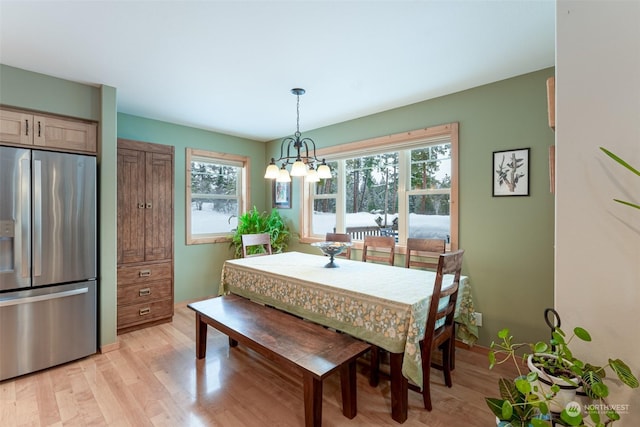 dining space featuring light wood-type flooring and an inviting chandelier