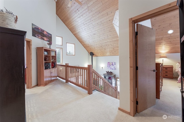 hall featuring light colored carpet, wooden ceiling, and high vaulted ceiling