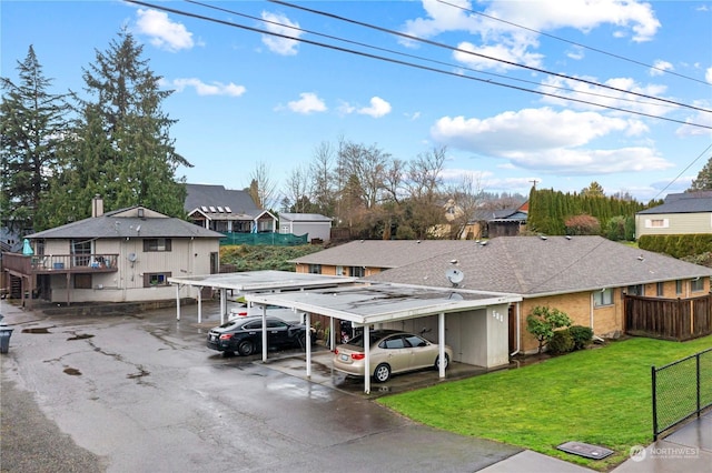 view of front of property with a front lawn, fence, a residential view, covered parking, and roof with shingles