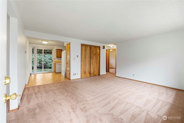 unfurnished room featuring a textured ceiling and light carpet