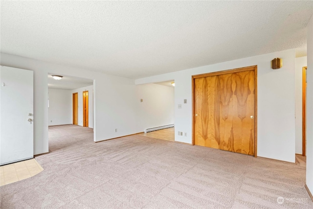 carpeted spare room with a textured ceiling and baseboard heating