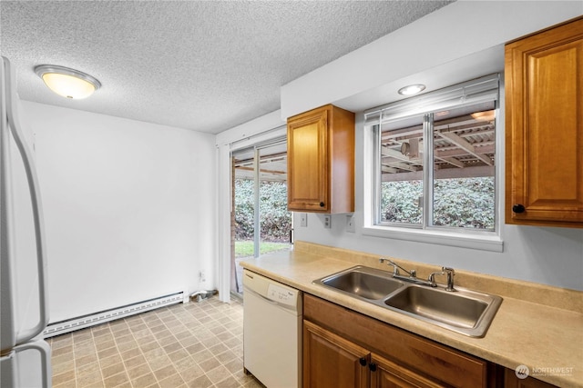 kitchen with a sink, a baseboard heating unit, a textured ceiling, white appliances, and light countertops