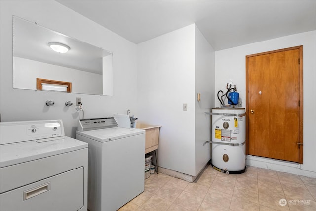 laundry area featuring baseboards, light tile patterned floors, laundry area, secured water heater, and independent washer and dryer