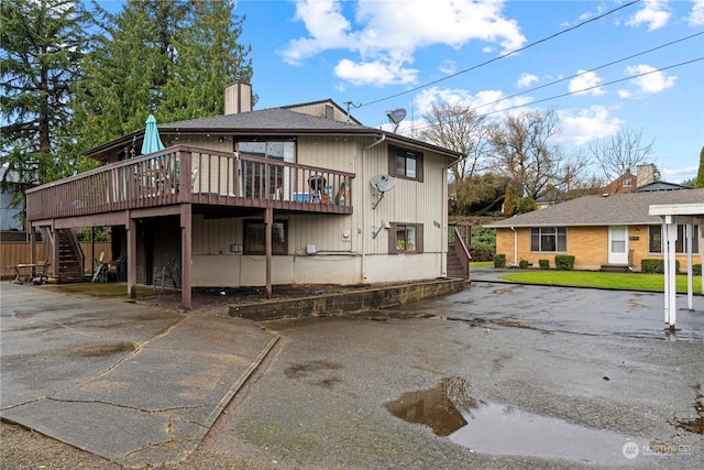 back of house with stairway, a lawn, a deck, and a chimney