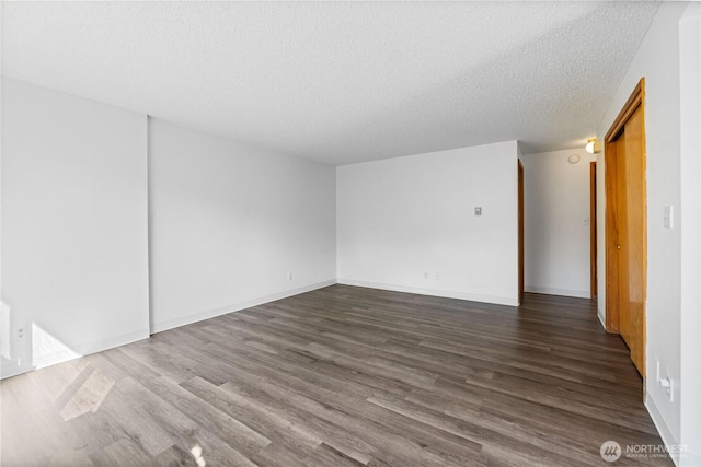 empty room with baseboards, dark wood-style flooring, and a textured ceiling