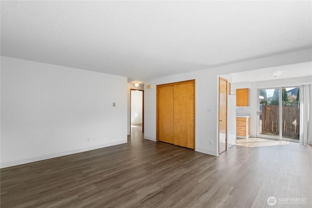 interior space with baseboards, a textured ceiling, and dark wood-style flooring