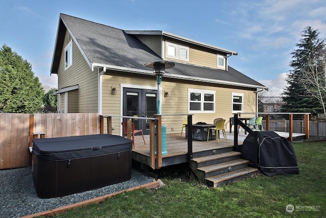 back of property featuring a yard, a wooden deck, and a hot tub