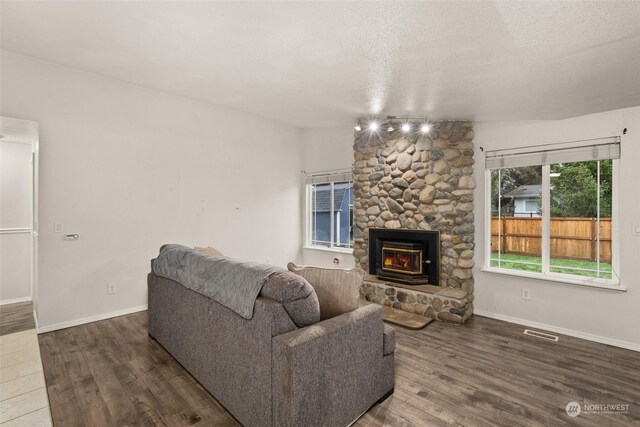 living room featuring a fireplace, a textured ceiling, and dark hardwood / wood-style floors