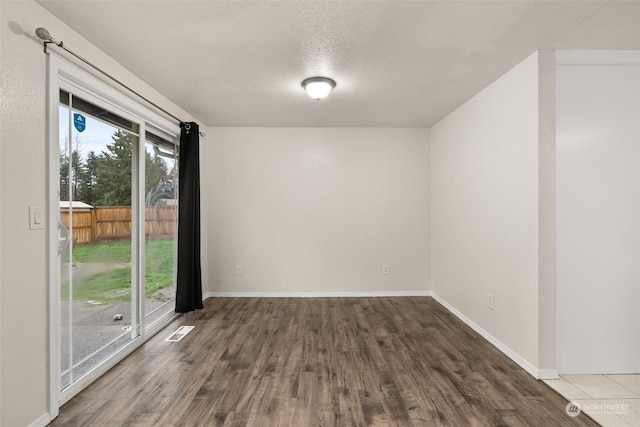 empty room with a textured ceiling and dark hardwood / wood-style flooring