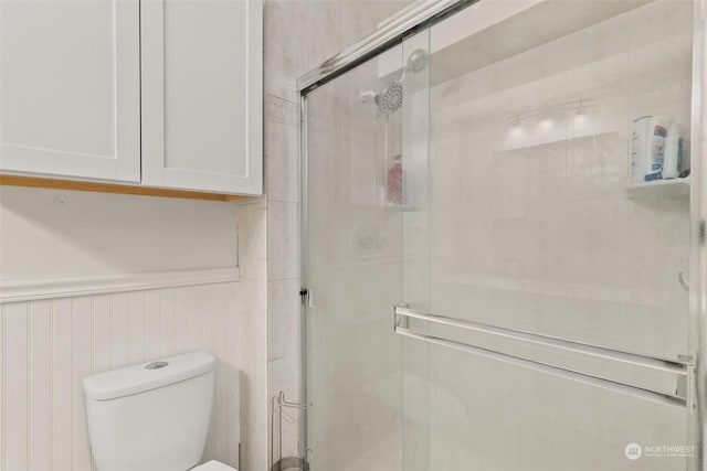 bathroom featuring toilet and a shower with shower door