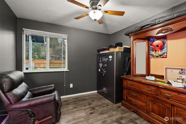 sitting room with a textured ceiling, ceiling fan, and dark wood-type flooring