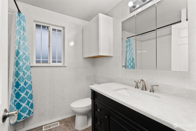 bathroom featuring tile patterned floors, vanity, toilet, and tile walls