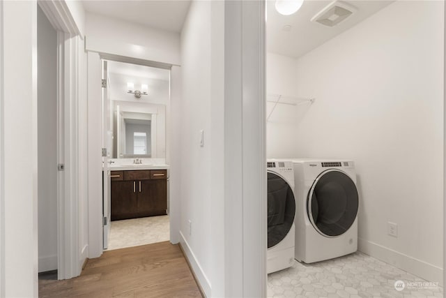 washroom featuring sink, washer and dryer, and light hardwood / wood-style flooring