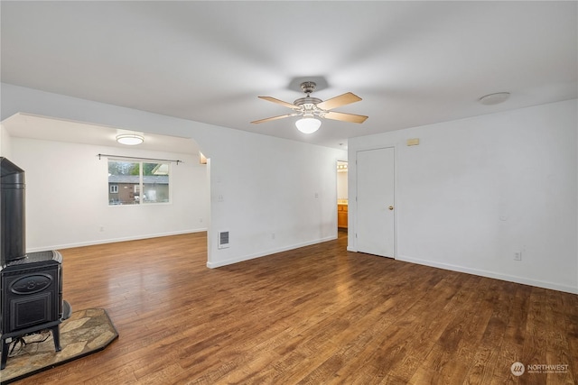 living room featuring hardwood / wood-style floors, a wood stove, and ceiling fan