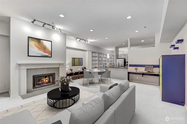 carpeted living room with a tiled fireplace and rail lighting