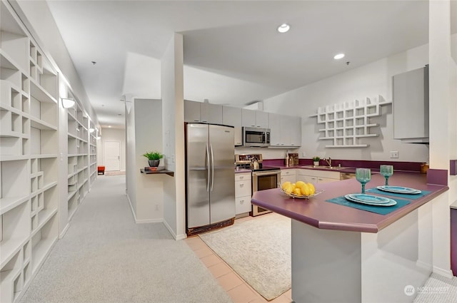 kitchen featuring sink, a breakfast bar area, gray cabinetry, appliances with stainless steel finishes, and kitchen peninsula