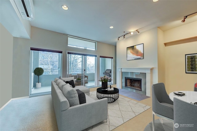 carpeted living room featuring a tile fireplace and rail lighting