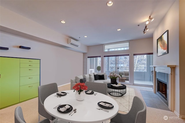 dining area with an AC wall unit, track lighting, and a fireplace