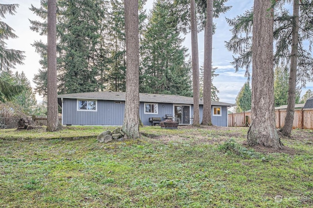 rear view of property with an outdoor fire pit and a lawn