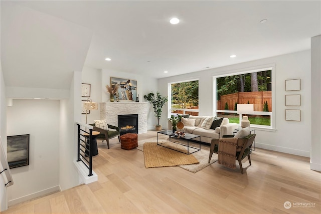 living room with a stone fireplace and light hardwood / wood-style flooring