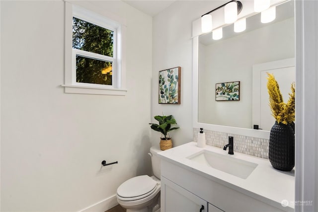 bathroom with toilet, vanity, and decorative backsplash