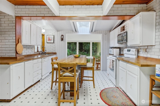 kitchen with white appliances, wooden counters, white cabinetry, a skylight, and beamed ceiling