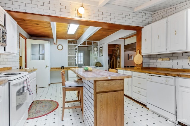 kitchen with butcher block countertops, white appliances, beamed ceiling, and white cabinets