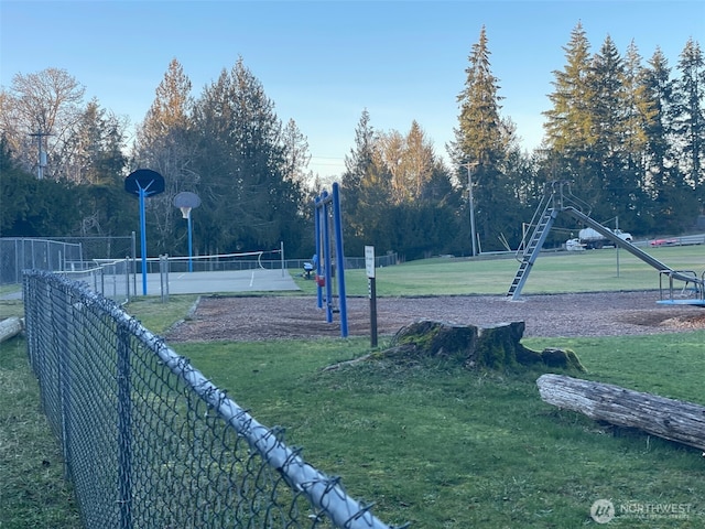 view of community with basketball hoop, a lawn, and a playground