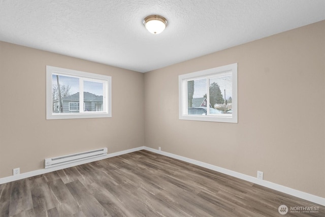 spare room with baseboards, a textured ceiling, baseboard heating, and wood finished floors