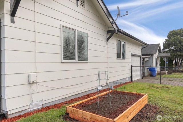 view of side of home with a lawn, fence, and a garden