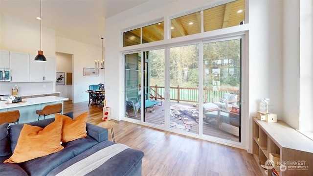 doorway to outside featuring a towering ceiling, light wood-type flooring, and an inviting chandelier