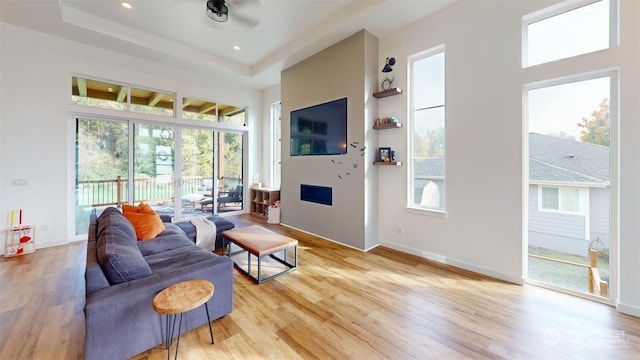 living room featuring a tray ceiling, ceiling fan, and light hardwood / wood-style floors