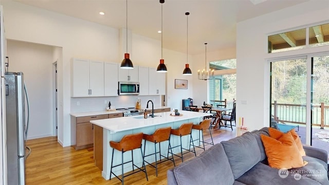 kitchen featuring appliances with stainless steel finishes, a wealth of natural light, sink, pendant lighting, and a center island with sink