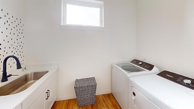 washroom featuring washer and dryer, light hardwood / wood-style floors, cabinets, and sink