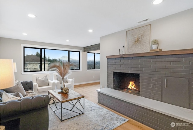 living room featuring wood-type flooring and a brick fireplace